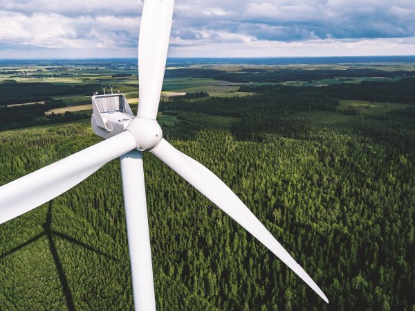 Aerial view of windmills in green summer forest in Finland close up. Wind turbines for electric power with clean and Renewable Energy
