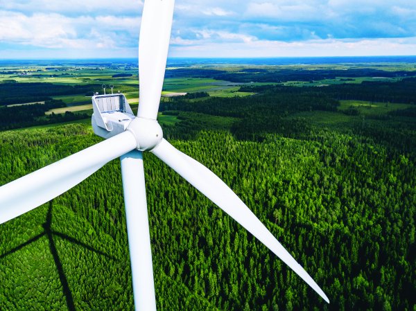 Aerial view of windmills in green summer forest in Finland close up. Wind turbines for electric power with clean and Renewable Energy