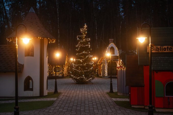 Ar lampiņām rotāta eglīte un iedegtas laternas pie mazajiem rūķu namiņiem Latvijas valsts mežu dabas parkā Tērvetē