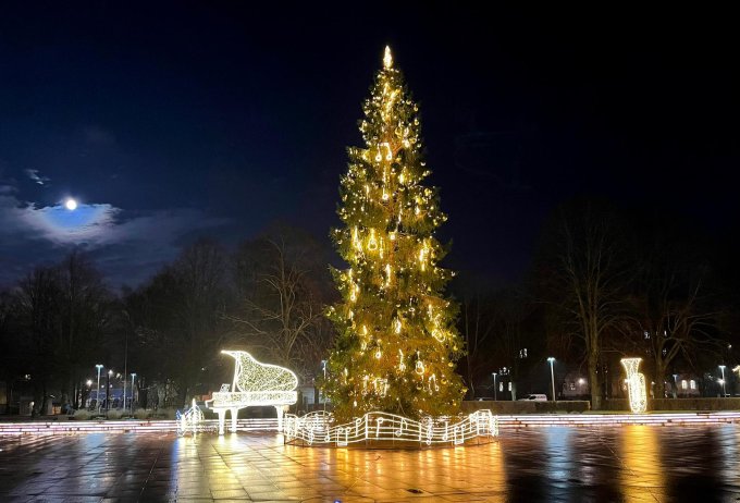 Gaiši izgaismota Ziemassvētku egles Ventspils pilsētas laukumā tumšā vakarā