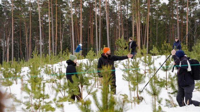 Ekspedīcijas vadītājs sniegotā jaunaudzē māca skolēniem noteikt koku skaitu vienā hektārā
