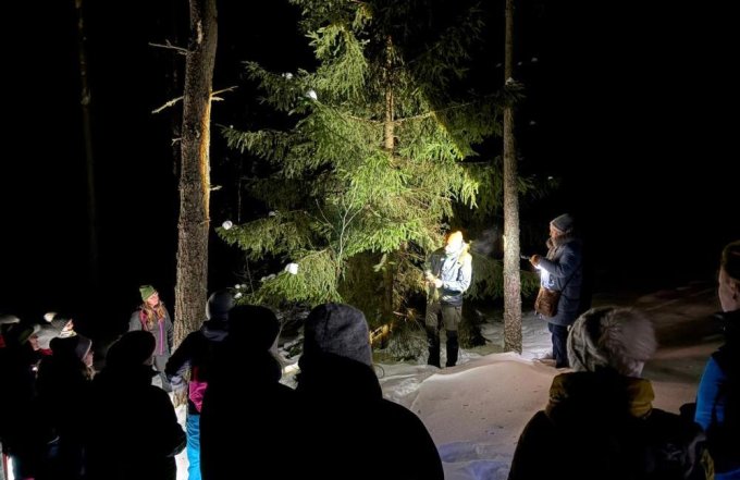 Pārgājiena dalībnieki mežā tumsā sarunājas