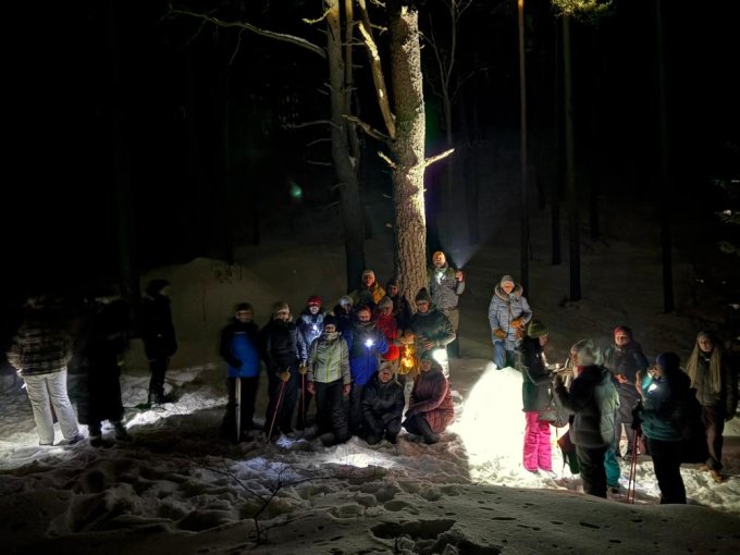 Skolotāji drosmes pargajienā tumsā iet pa sniegotu meža taku