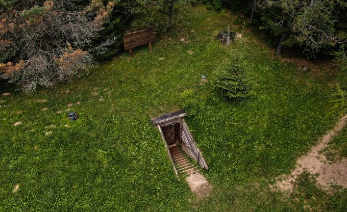No drona bildēts pazemes bunkurs, kur redzamas koka kāpnes